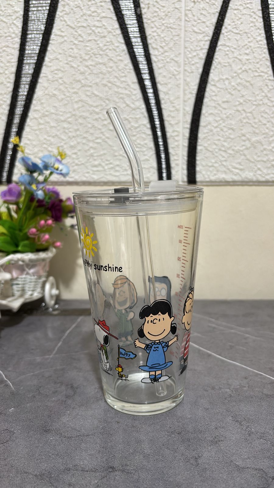 Clear tumbler with cartoon characters and text on a gray surface