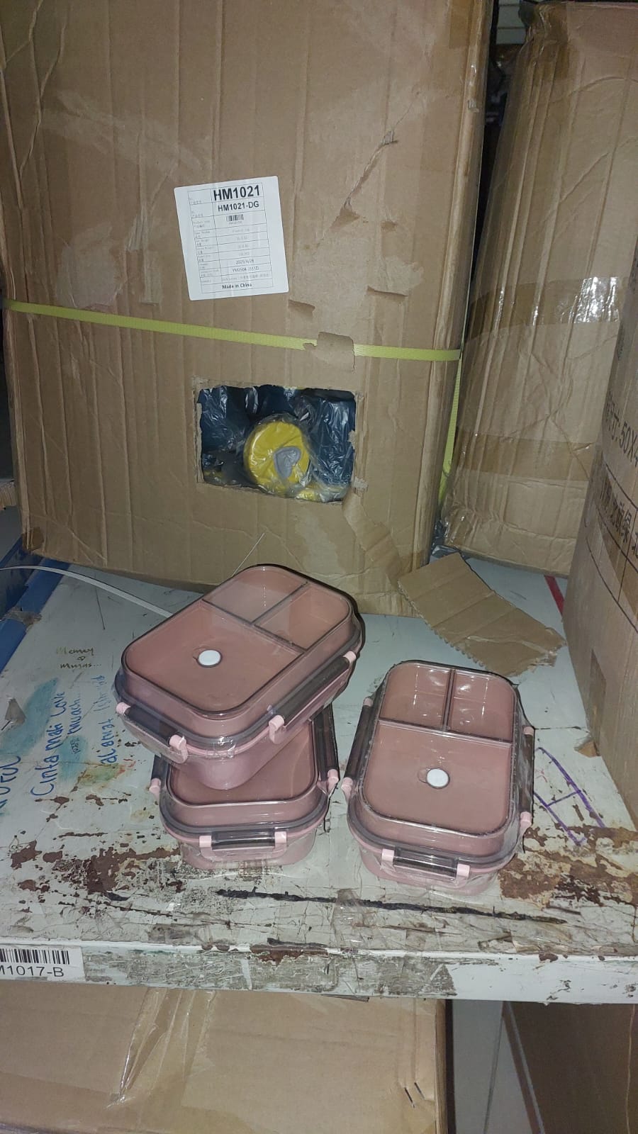 Brown plastic containers on a cardboard floor with a box in the background