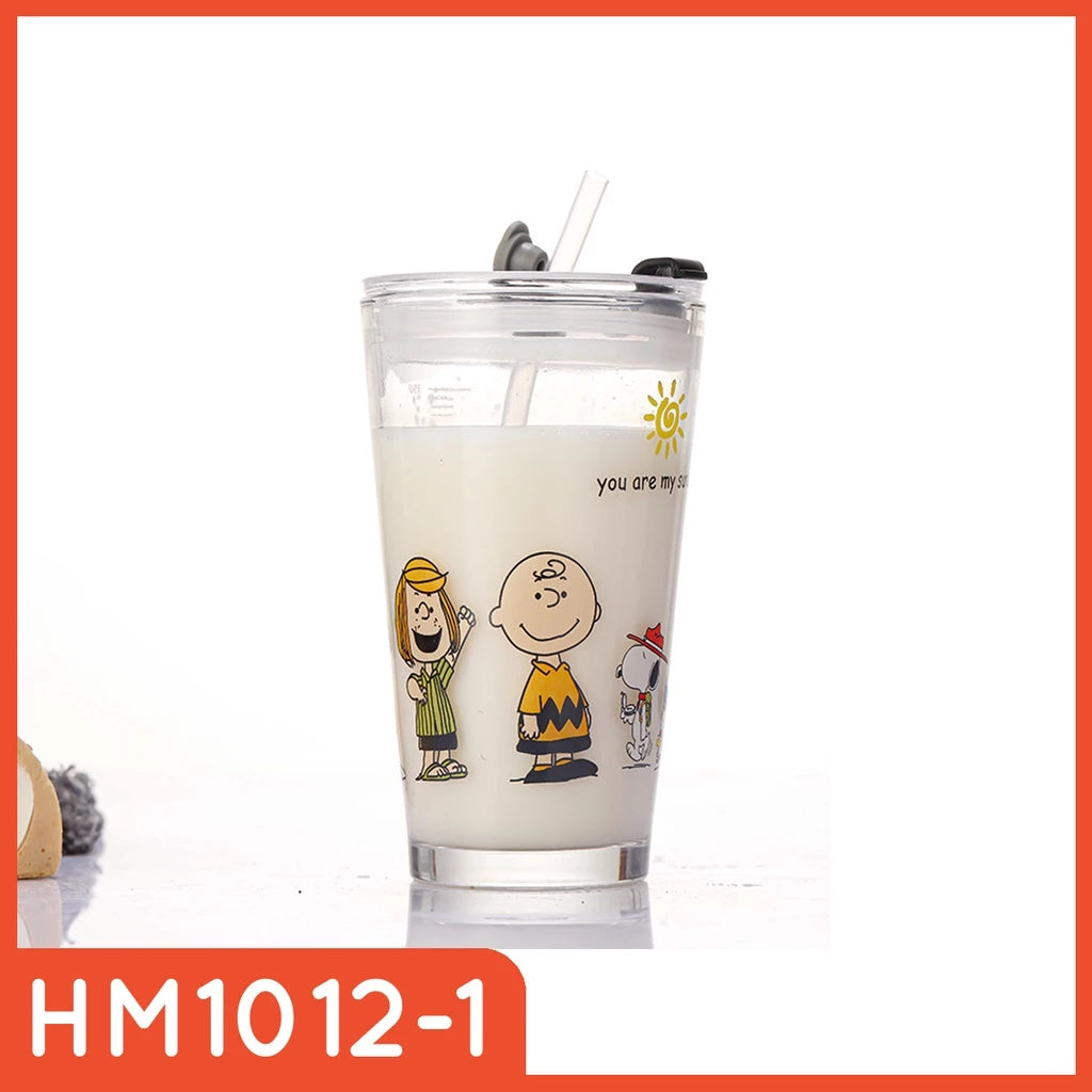 Gelas tumbler kaca transparan berisi cairan putih dengan sedotan, tutup hitam, dan dihiasi gambar karakter Snoopy, Charlie Brown, dan Woodstock. Terdapat tulisan "you are my sunshine" di dekat ilustrasi matahari.