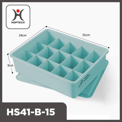 "Tampilan tiga perempat dari organizer laci Hoptech HS41-B-15 berwarna biru kehijauan pastel dengan 15 kompartemen terpisah dan penutupnya di bawah. Dimensi produk terlihat jelas: panjang 31cm, lebar 24cm, dan tinggi 9cm. Logo Hoptech berwarna merah dan hitam tertera di pojok kiri atas gambar. Ikon kaus kaki dan celana dalam terlihat di sisi kotak, menunjukkan fungsinya untuk penyimpanan pakaian dalam atau kaus kaki."