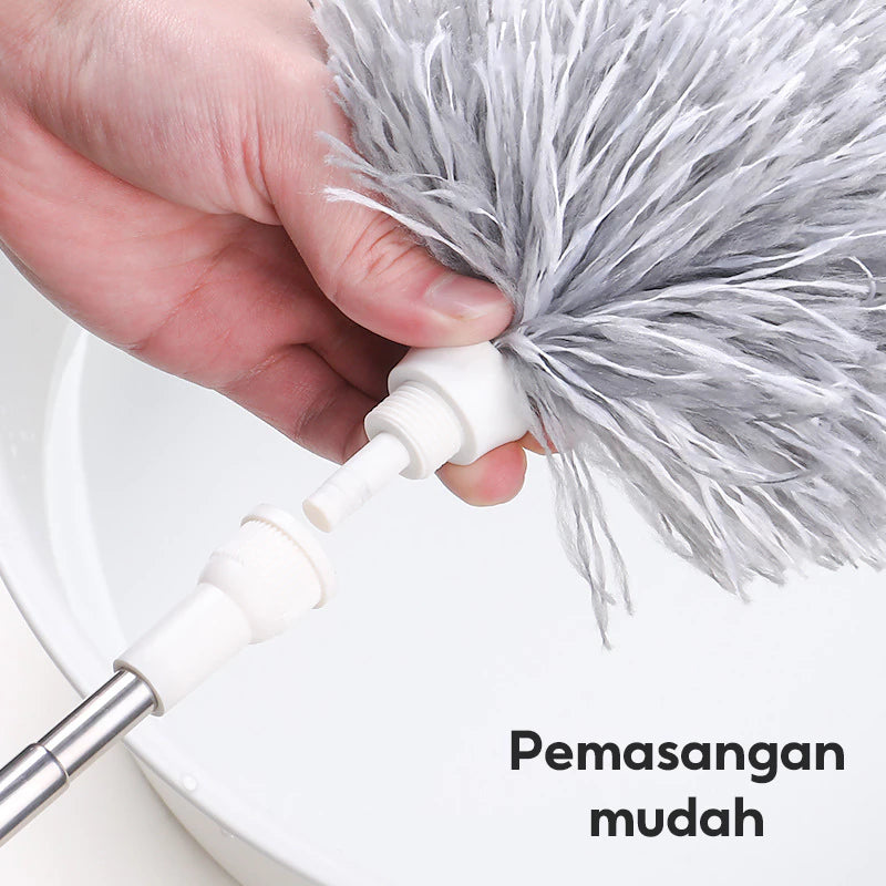 Gambar ini menunjukkan tangan yang sedang memasang kepala kemoceng microfiber berwarna abu-abu ke gagang putih yang dapat dilepas. Terdapat tulisan "Pemasangan mudah" di sudut kanan bawah gambar. Latar belakangnya adalah permukaan putih yang buram, kemungkinan wastafel atau wadah, dengan titik biru di atasnya.