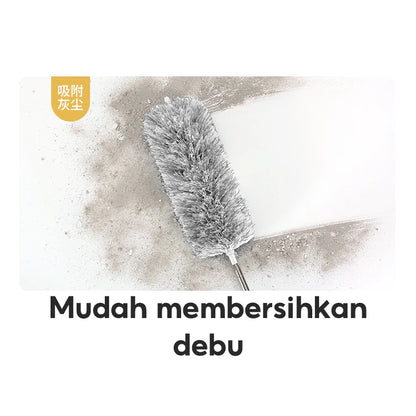 Gambar ini menunjukkan sebuah kemoceng microfiber berwarna abu-abu yang sedang membersihkan atau menyapu permukaan yang kotor dan berdebu. Sebagian permukaan sudah bersih dan berwarna putih, sementara sebagian lainnya masih terlihat banyak debu.