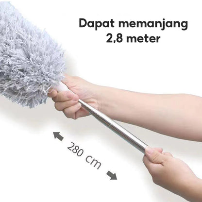 Gambar ini menunjukkan tangan yang memegang gagang kemoceng berwarna perak yang dapat dipanjangkan (teleskopik). Kepala kemoceng microfiber berwarna abu-abu terlihat di ujung gagang. Ada panah hitam yang menunjuk ke kiri dan ke kanan dengan tulisan "280 cm" di antara panah tersebut, menunjukkan panjang maksimal gagang. Di bagian atas gambar, terdapat teks besar berwarna hitam yang bertuliskan "Dapat memanjang 2,8 meter". Ini mengindikasikan fitur kemoceng yang bisa diperpanjang hingga 2,8 meter atau 280 cm.