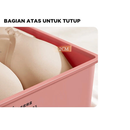 Penampakan sisi atas kotak penyimpanan berwarna merah muda pastel, menunjukkan bagian tepi wadah setinggi 2cm, ideal untuk menyimpan bra berwarna krem yang terlihat rapi di dalamnya. Terdapat teks 'BAGIAN ATAS UNTUK TUTUP' berwarna putih di latar belakang hitam, mengindikasikan bahwa wadah ini dilengkapi tutup."